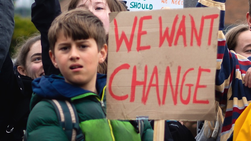 Exeter youth climate strikers holding placard reading "We want change"