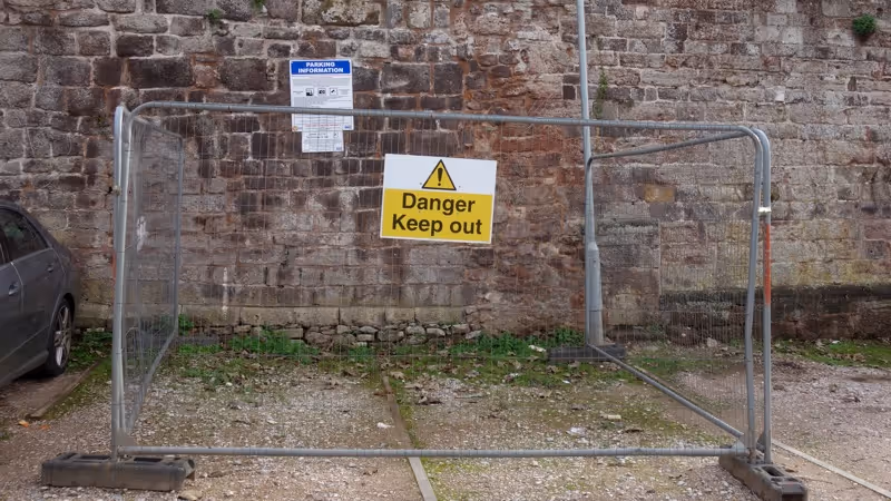 Heras fencing in front of an unsafe section of Exeter city wall in Northernhay Street car park