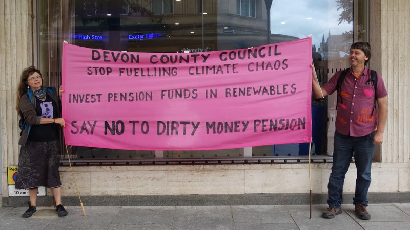Protestors hold Devon County Council stop funding fossil fuel companies banner in Bedford Square